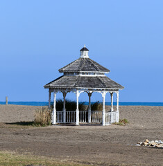 Empty outdoor gazebo on the sand beach in winter under blue sky