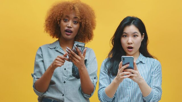 Two young women checking social networks and showing their surprise with wierd face expression. High quality 4k footage
