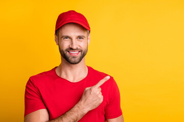 Photo of cheerful bearded guy direct finger empty space wear red t-shirt headwear isolated yellow...