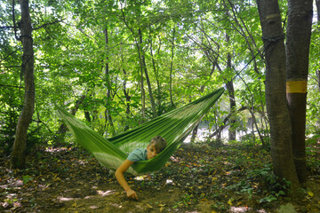 Teenage boy lying in a hammock in the wood. Guamskoye gorge, Krasnodar Krai, Caucasus, Russia.