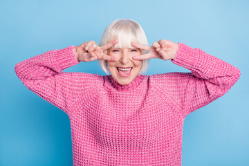Photo portrait of cool old lady showing two v-signs near eyes isolated on pastel blue colored background