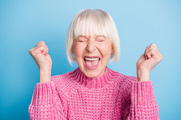 Portrait of astonished aged woman fists up closed eyes open mouth shout wear sweater isolated on...