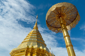 close-up top part of golden pagoda and umbrella at Wat Phra That Doi Suthep in blue cloud sky, Phra That Doi Suthep temple in Chiang Mai, Thailand, travel destination