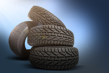 Stack of four new black tyres for winter car on blue background