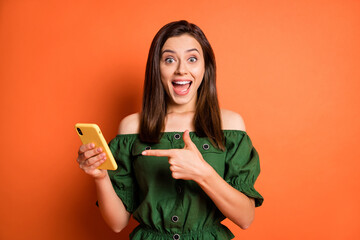 Photo of optimistic girl point telephone wear dark shirt isolated on orange color background