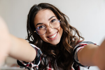 Cheerful nice woman in eyeglasses smiling and taking selfie photo