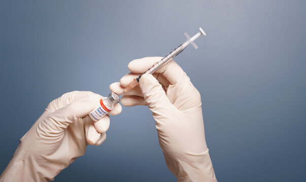 Covid-19, 2019-nCoV vaccination development concept. Beautiful close up - Doctor's hands in medical latex gloves takes shot from Coronavirus Vaccine vial by sterile needle syringe. Phase 3, FDA, WHO.