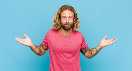 blonde man feeling puzzled and confused, doubting, weighting or choosing different options with...