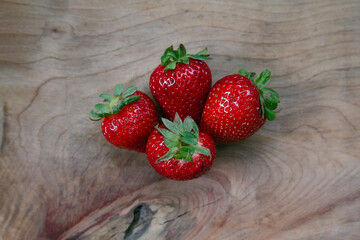 delicious fresh strawberries, a strong red on a rustic wooden table and a white brick wall background