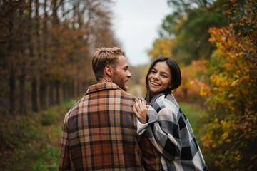 Beautiful happy couple smiling and hugging while strolling in forest
