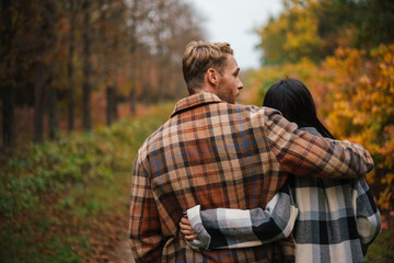 Beautiful romantic couple hugging while strolling in autumn forest