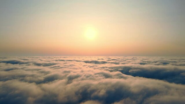Flying over the clouds at sunset. The sun rises over the fog. Orange sunset over the fog.