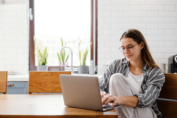 Happy beautiful woman working with laptop while sitting at table