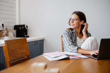 Cheerful beautiful woman doing homework with laptop