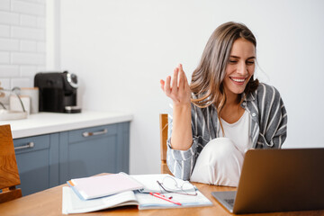 Cheerful beautiful woman gesturing while making video call on laptop