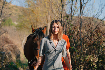 Two women friends chatting and taking a ride with their horse through the countryside