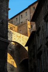 Stone arch on top of medieval building, illuminated by orange sunset light, city of Perugia, Umbria region, Italy