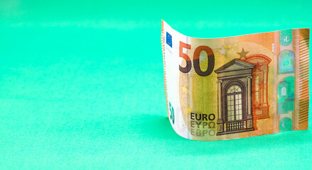 Paper bill with a face value of 50 euros on a green background. Free space for copying.