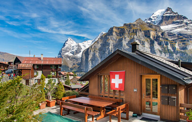 Wood chalet with Swiss flag in mountain village Murren at Jungfrau region, Switzerland.