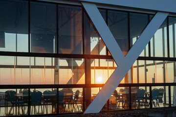 Sunlight shines through a glass wall of a building on the beach, beautiful sunset sky and sea background