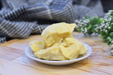 Natural cocoa butter oil in a wooden bowl on a brown background
