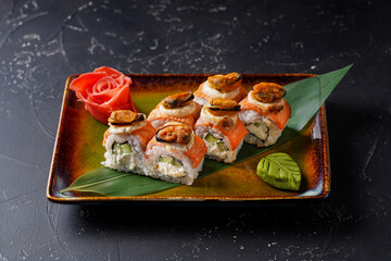 Baked roll Philadelphia with mussels, salmon, cream, cucumber. On black background.