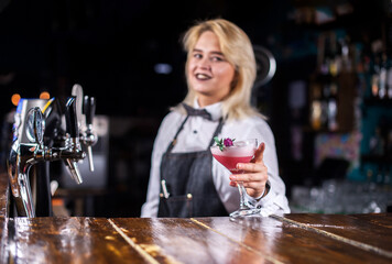 Girl barman creates a cocktail on the alehouse
