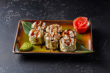 Snow crab sushi roll. On a plate on a black background. © Daniil