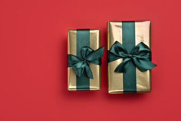 Two Christmas gift boxes with satin ribbons  on red background. Trendy design in color of 2021. Top...