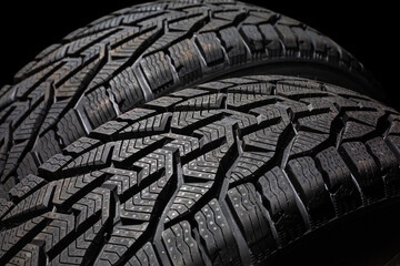 Closeup car tire isolated on black background. Wet with drops wheel against black