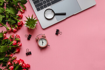 Beautiful workplace with laptop, alarm clock, flowers, and magnifying glass on pink background with copy space. Business, freelance and education concept. Top view, flat lay, copy space for design