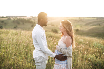 Sun rays shine through a pregnant couple. Tenderly future parents enjoying time together outdoors