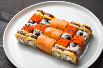 set of various sushi on white plate on wooden table background. Rolls of philadelphia and other.