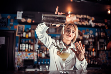 Sweet woman bartending formulates a cocktail