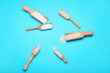 Scoops with rice and flour on color background