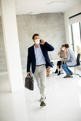 Young business man walking and using mobile phone while wear protective masks to prevent  corona viruus at office space