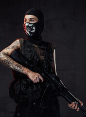 Dark portrait of pretty military woman weared with mask and with tattoo on her right hand holding...