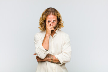 blonde man feeling bored, frustrated and sleepy after a tiresome, dull and tedious task, holding...