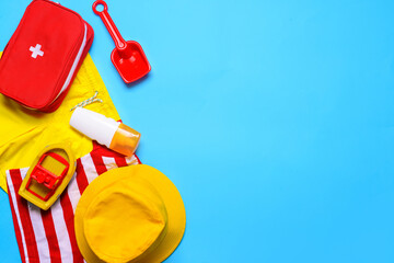Composition of little boy beach accessories with first aid kit on color background