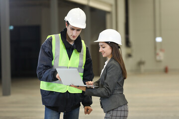 Portrait of a female factory manager in a white hard hat and business suit and factory engineer in work clothes. Controlling the work process in the helicopter manufacturer.	