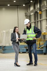 Portrait of a female factory manager in a white hard hat and business suit and factory engineer in work clothes. Controlling the work process in the helicopter manufacturer.	