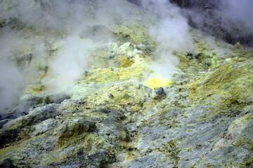 a rocky volcanic landscape with sulphur geysers smoking away 