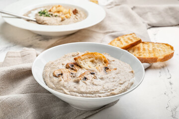 Bowl of tasty mushroom cream soup on light background