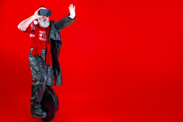 Happy modern Santa Claus riding on fast black monowheel wearing virtual reality 3d glasses and biker clothes. Winter and new tears eve holiday celebration concept. © Monstar Studio