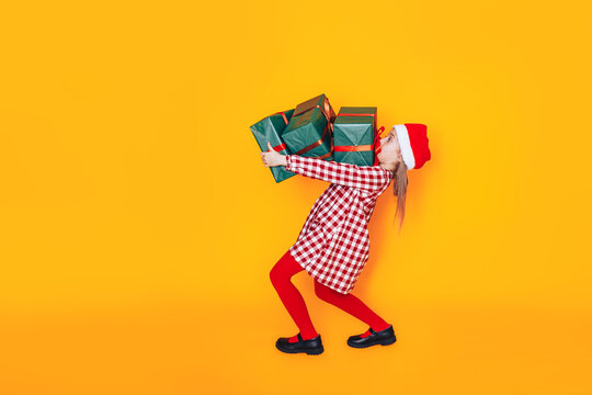 Child holding large boxes with gifts. There is a hat on his head. Christmas mood. Perfect photo for Christmas advertising