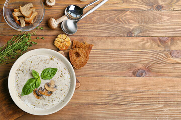 Fototapeta na wymiar Bowl with tasty mushroom cream soup on wooden background