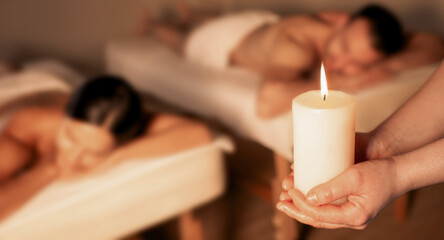 Aromatherapy, hot oil massage. Aromatherapy candle in hands of a massage therapist before a hot oil massage for a beautiful couple