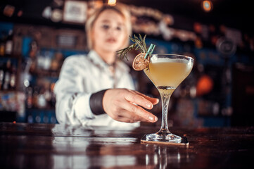 Young girl mixologist is pouring a drink in the nightclub