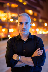 Portrait of confident man at night on the streets arms crossed