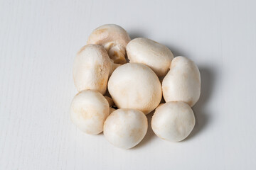 White champignon mushrooms are isolated on a white table.